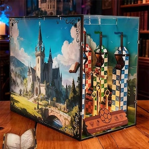May include: A rectangular display box featuring a printed scene of a stone castle on the exterior side panel. The interior contains three vertical towers with red, green, and blue checkered patterns, and a sign labelled Magic Flying Ball Competition.