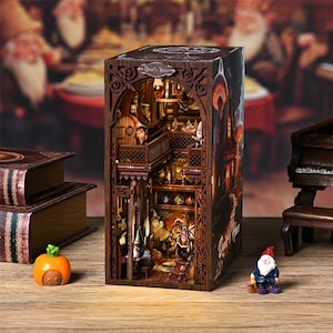 May include: A detailed wooden diorama of a fantasy scene, featuring multiple levels with miniature figures, intricate architectural details, and warm lighting. The exterior is dark brown with the text "Devil's House". A small pumpkin and gnome figurine are in the foreground.