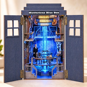 Könnte beinhalten: Eine blaue Holzkiste mit dem Text "Mysterious Blue Box" oben. Die Kiste öffnet sich und zeigt ein detailliertes Inneres mit einer Figur, blauen Lichtern und komplizierten mechanischen Details. Die Kiste hat zwei Türen mit Fenstern.