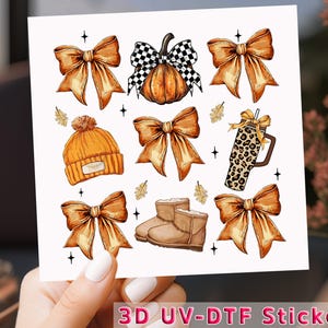 May include: A sheet of 3D UV-DTF stickers featuring fall-themed illustrations. The designs include orange bows, a pumpkin with a checkered bow, a beanie, a leopard-print tumbler, and brown boots. The text "3D UV-DTF Sticker" is visible.