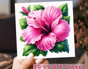 May include: A vibrant pink hibiscus flower sticker with green leaves and a bud. The sticker has the text "3D UV-DTF Sticker" at the bottom. The flower is the focal point, with detailed petals and a dark center.