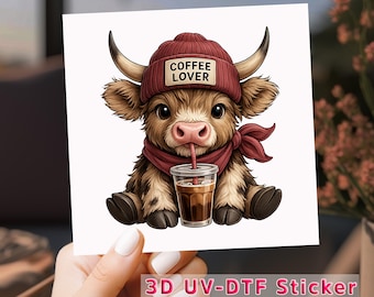 Puede incluir: Una pegatina con un ternero de dibujos animados con un gorro rojo con el texto "COFFEE LOVER", una bufanda roja y bebiendo café. El ternero tiene pelaje marrón y cuernos. La pegatina está etiquetada como "3D UV-DTF Sticker".