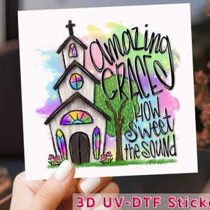 May include: A 3D UV-DTF sticker with a watercolor background featuring a church, a tree, and the words "Amazing Grace How Sweet The Sound".