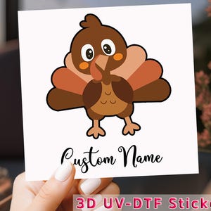 May include: A white square sticker featuring a cartoon turkey with brown, tan, and orange feathers. The text "Custom Name" is written in cursive, and the words "3D UV-DTF Sticker" are at the bottom.