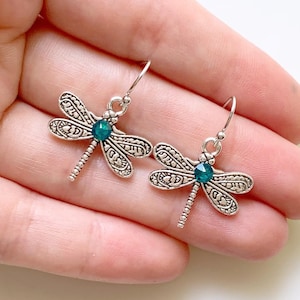 May include: Silver dragonfly earrings with green crystal accents.