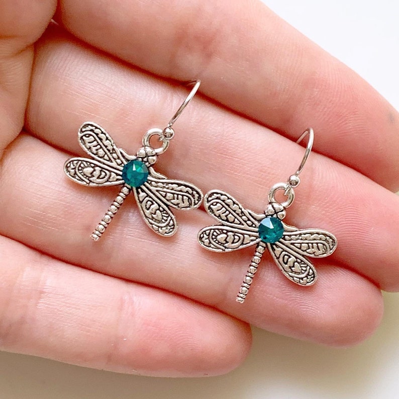 May include: Silver dragonfly earrings with green crystal accents.