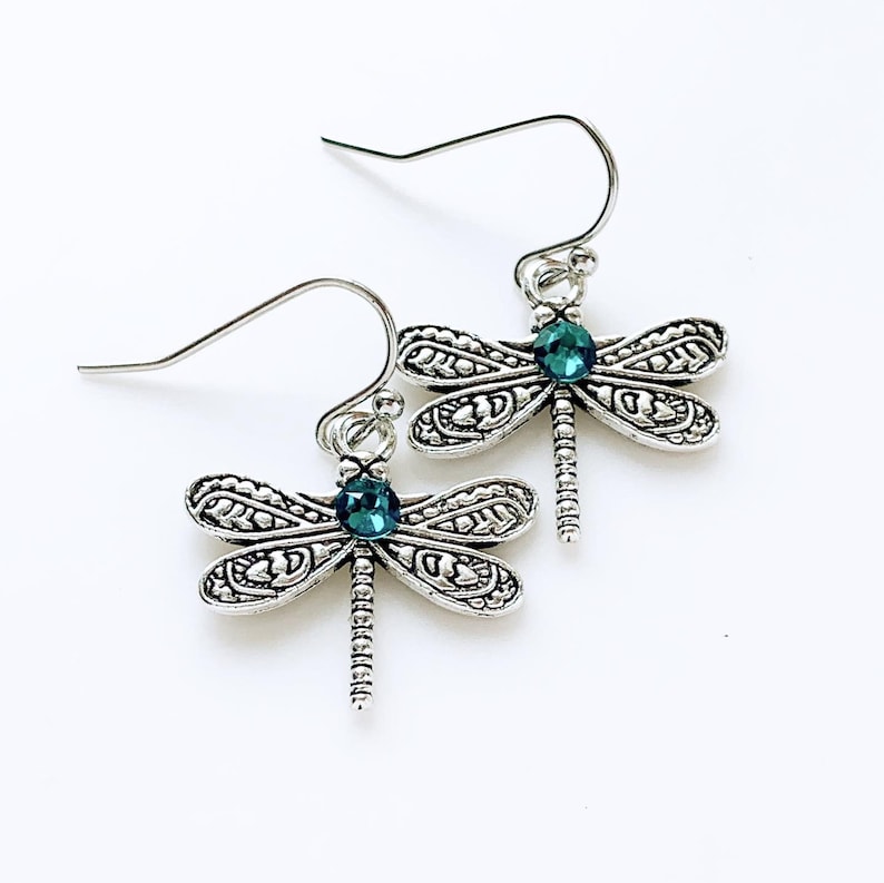 May include: Silver dragonfly earrings with teal blue crystal accents.