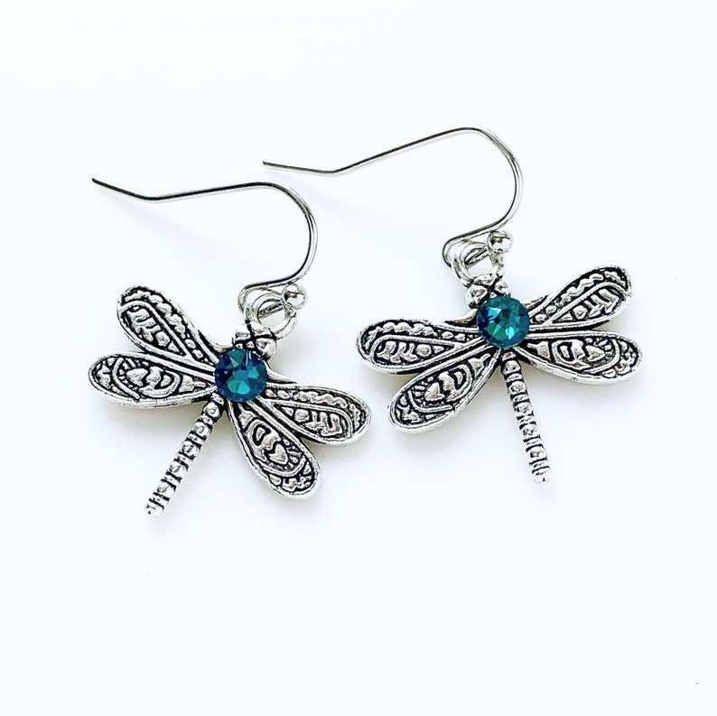 May include: Silver dragonfly earrings with teal blue crystal accents.