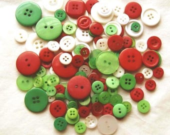 May include: A collection of assorted round buttons in various sizes and shades of red, green, and white. The buttons feature two or four holes for sewing and are made of smooth plastic, with some variations in opacity and finish.