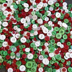 Puede incluir: Una gran colección de botones surtidos en colores rojo, blanco y verde. Los botones son de varios tamaños y formas.