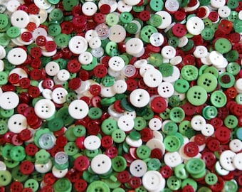 May include: A collection of various sizes of buttons in red, green, and white. The buttons have two or four holes and are scattered across the image. Some buttons have a glossy finish, while others are matte.