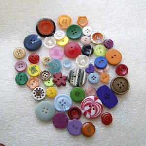 May include: A collection of assorted sewing buttons in various shapes, sizes, and colors, including round, flower-shaped, and rectangular designs. The buttons feature different textures, patterns, and hole counts, rendered in shades of red, blue, green, yellow, purple, orange, and brown.