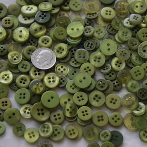 May include: A large collection of green plastic buttons in various sizes and styles. The buttons have two, four, or six holes.