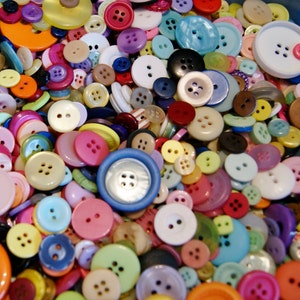 May include: A collection of colorful buttons in various shapes and sizes. The buttons are made of plastic, metal, and fabric. Some buttons have a shiny finish, while others have a matte finish.