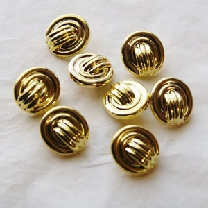 May include: Eight gold-toned buttons with a woven design. The buttons are round and have a raised, textured surface.