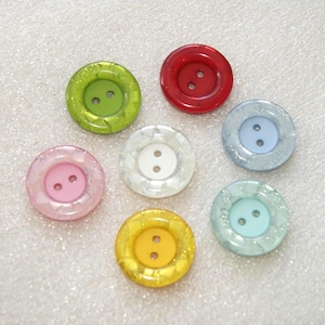 Puede incluir: Colección de siete botones redondos y coloridos. Los botones son de varios colores, incluyendo rojo, verde, rosa, blanco, amarillo y azul. Cada botón tiene dos agujeros para coser y un anillo exterior brillante.