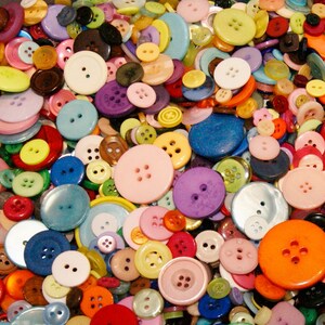 May include: A large collection of colorful buttons in various shapes and sizes. The buttons are made of plastic, metal, and fabric. They are arranged in a random pattern and some are overlapping.