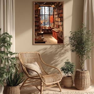 A framed illustration of a bookstore with autumn trees outside, hanging on a light beige wall next to a wicker chair and potted plants.