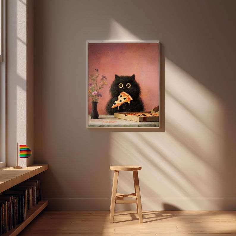 Puede incluir: Impresi&oacute;n enmarcada que muestra un gato negro comiendo una porci&oacute;n de pizza. El gato tiene grandes ojos amarillos y est&aacute; situado frente a un fondo rosa. Tambi&eacute;n se ve una caja de pizza y un jarr&oacute;n con flores.