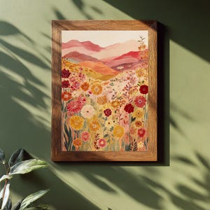 May include: A framed watercolour print depicting a colourful wildflower meadow with a mountain backdrop. The artwork features a variety of flowers in shades of red, yellow, and pink. The wooden frame adds a rustic touch to the artwork.