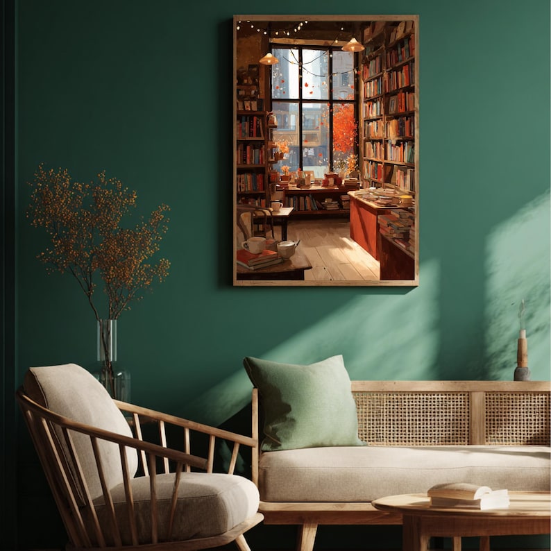 A framed illustration of a bookstore with autumn trees outside, hanging on a dark green wall above a light-colored sofa and wooden chair.