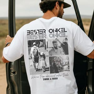 May include: White t-shirt with the text "BESTER ONKEL" and a collage of black and white photos. The shirt has a relaxed fit and is worn by a person standing next to a vehicle.