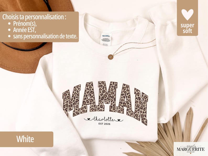 Op de afbeelding: Witte sweatshirt met het woord "MAMAN" in een luipaardprint. Daaronder de naam "Charlotte" en het jaar "EST 2026". De sweatshirt heeft een "super soft" label.