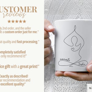 May include: White ceramic mug featuring a minimalist line drawing of a yoga pose with a heart. The mug has the word "namaste" and the name "Sophie" in a delicate script. The mug is held by a person.
