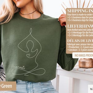 May include: Military green sweatshirt with a white line drawing of a yoga pose and the word "namaste". The sweatshirt is made of a soft material and is perfect for yoga enthusiasts.