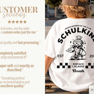 May include: A white t-shirt featuring a black graphic on the back. The design includes the text PROUD MEMBER OF THE CLUB SCHULKIND, a cartoon character wearing sunglasses, the text EST 2026, EINFACH 1. KLASSE, and the name Noah with checkered borders.