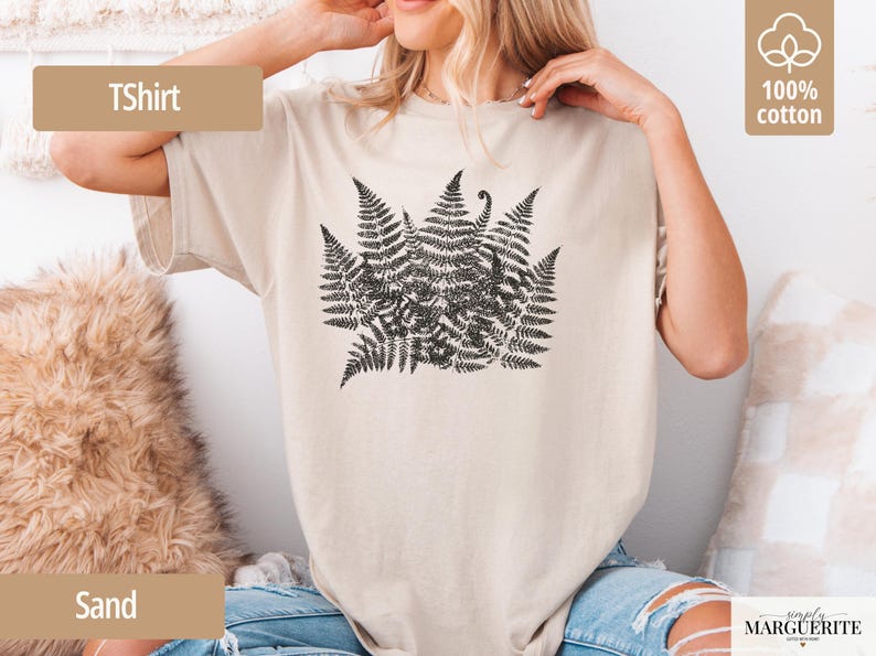 Puede incluir: Camiseta color arena con un dise&ntilde;o de helecho negro. La camiseta tiene mangas cortas y cuello redondo. El texto "TShirt" est&aacute; en un rect&aacute;ngulo marr&oacute;n en la parte superior izquierda. Hecha de 100% algod&oacute;n.