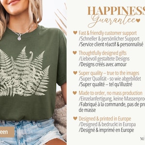 Puede incluir: Camiseta verde militar con un dise&ntilde;o de helecho crema. La camiseta tiene cuello redondo y mangas cortas. El texto "HAPPINESS Guarantee" es visible en la imagen.