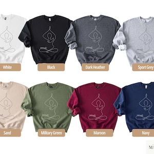 May include: A collection of eight crewneck sweatshirts in various colors, including white, black, and navy. Each sweatshirt features a minimalist yoga pose design in white and the word "namaste". The sweatshirts are labeled with their respective colors.