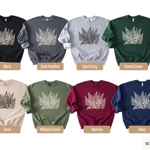 Puede incluir: Una colecci&oacute;n de sudaderas de cuello redondo en varios colores, incluyendo negro, gris oscuro, gris deportivo, verde bosque, arena, verde militar, granate y azul marino. Cada sudadera presenta un dise&ntilde;o de helecho.