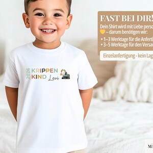 May include: A white short-sleeved t-shirt featuring a graphic print with the text 2026 KRIPPEN KIND and the name Levi in cursive script, accompanied by a small illustration of a green and yellow construction excavator vehicle.