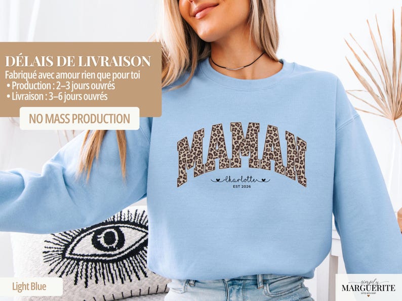 Op de afbeelding: Lichtblauw sweatshirt met het woord "MAMAN" in een luipaardprint. Onder het woord "MAMAN" staat de naam "Charlotte" en het jaar "EST 2026". Het sweatshirt is lichtblauw van kleur.