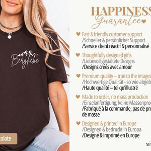 May include: Dark chocolate-colored t-shirt with the word "Bergfiebe" and a mountain graphic in white. The shirt has a crew neck and short sleeves. The text "Dark Chocolate" is at the bottom.