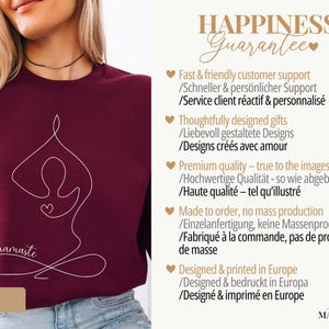 May include: Maroon sweatshirt with a white line drawing of a person in a yoga pose, with the word "namaste" in script. The sweatshirt has a crew neck and is made of a soft material. The text "HAPPINESS Guarantee" is in the background.