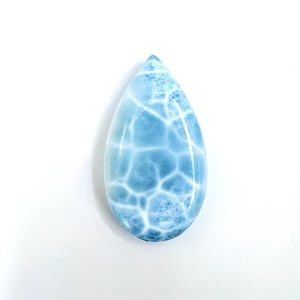 May include: A polished, teardrop-shaped gemstone with a light blue hue and a unique, web-like pattern of white veins. The stone is smooth and glossy, showcasing a natural, organic design. The gemstone is set against a white background.