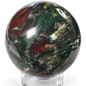 May include: A polished, spherical stone featuring a marbled pattern of deep forest green, dark burgundy, and white veins. The sphere is resting on a clear, circular acrylic stand, showcasing a smooth, reflective surface with natural mineral inclusions.