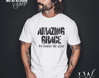 May include: White t-shirt with the text "AMAZING GRACE MY CHAINS ARE GONE" in a distressed black font. The shirt is a classic crew neck style. The image also includes the text "We are a NO AI DESIGN Shop" and a logo.