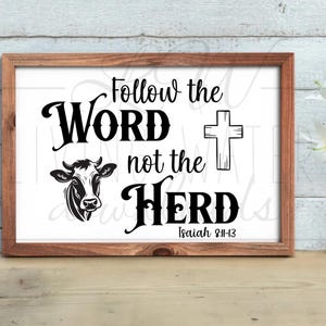 May include: A framed print with the words "Follow the Word not the Herd" in black script. A cow illustration and a cross are also featured. The text "Isaiah 8:11-13" is at the bottom. The frame is brown.