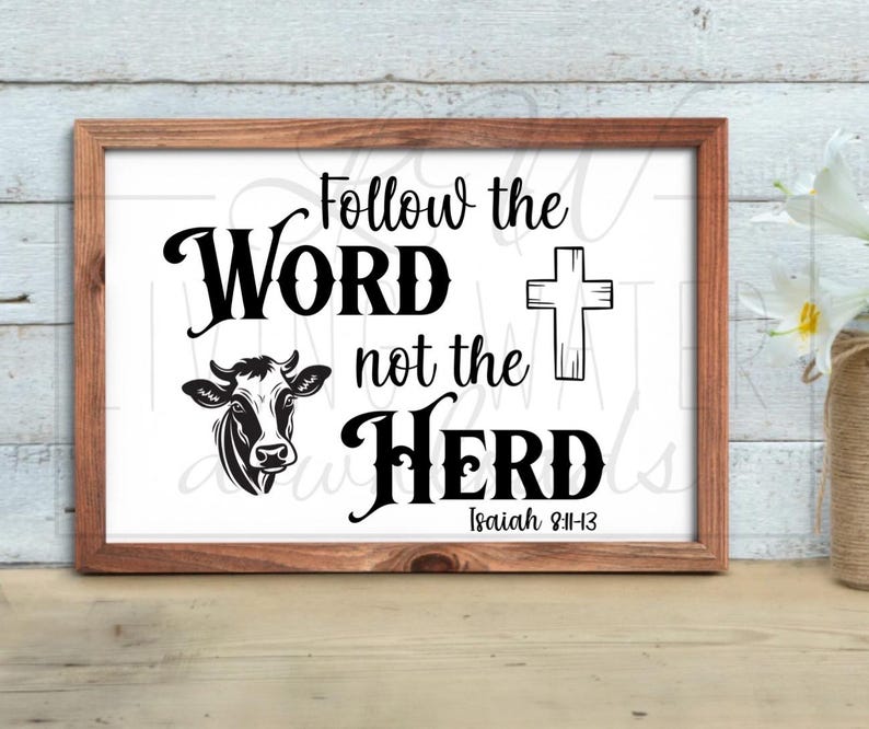 May include: A framed print with the words "Follow the Word not the Herd" in black script. A cow illustration and a cross are also featured. The text "Isaiah 8:11-13" is at the bottom. The frame is brown.