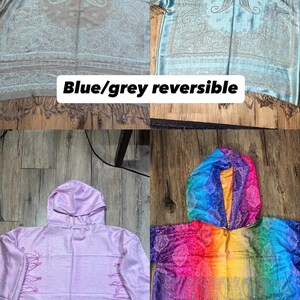 May include: Four hooded shawls in the image. The top left is blue/grey reversible, the top right is light blue, the bottom left is pink, and the bottom right is rainbow-colored. Each shawl has a paisley design and fringe.
