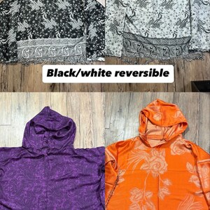 May include: Four hooded reversible jackets in black/white, purple, and orange. The black and white jackets have a paisley pattern. The purple jacket has a paisley pattern, and the orange jacket has a floral design. Each jacket has a fringed hem.