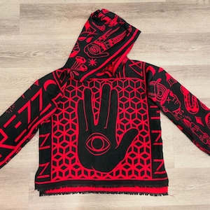 May include: Black and red hooded sweatshirt with a geometric hand and eye design. The sleeves and hood feature additional red patterns and the word "RENZ" in red. The bottom hem has a fringe.