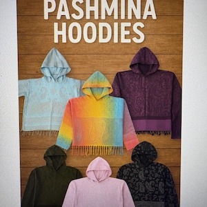 May include: An advertisement for Pashmina Hoodies. The image displays six hoodies in various colors, including light blue, rainbow, purple, green, pink, and black. Each hoodie has a hood and fringe at the bottom. The text "PASHMINA HOODIES" is at the top.