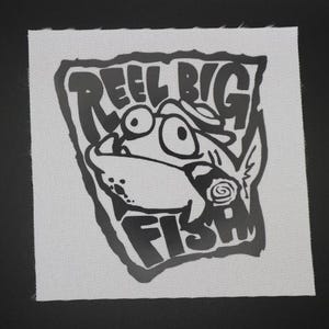 May include: A white square patch with a black cartoon illustration of a fish wearing a hat and a cigar. The text "REEL BIG FISH" is above and below the fish. The patch is on a black background.