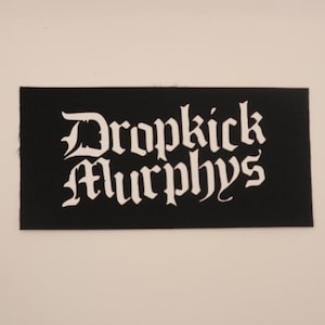 May include: White embroidered patch with the band name "Dropkick Murphys" in a gothic font on a black background.
