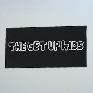 May include: A black rectangular patch with the white text "THE GET UP KIDS" in a bold, outlined font. The patch is likely made of fabric and is set against a plain white background.